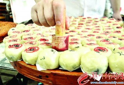 在生餅皮上面綴上黑芝麻，底部墊上白紙片后平整擺放。按傳統(tǒng)慣例，在生餅皮上蓋上鋪號印章。