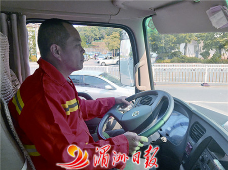 圖為灑水車司機張國慶在馬路上灑水作業(yè)。