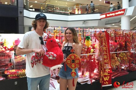 悉尼唐人街購物中心里，一家售賣中國傳統(tǒng)特色商品的店鋪顧客絡(luò)繹不絕，商鋪里里外外都掛滿了中國結(jié)、紅燈籠、春聯(lián)、年畫……正忙碌地招呼著顧客的朱太太是小店的老板，她喜氣洋洋對本報記者說：“我在唐人街開店12年了，春節(jié)前后是每年生意最好的時候。現(xiàn)在，許多澳大利亞當(dāng)?shù)厝撕陀慰投枷矚g采購一些中國結(jié)、燈籠等裝飾品，給家里”澳大利亞姑娘格蕾絲對圖為顧客正在挑選春節(jié)裝飾品。（人民網(wǎng)記者鮑捷 攝）