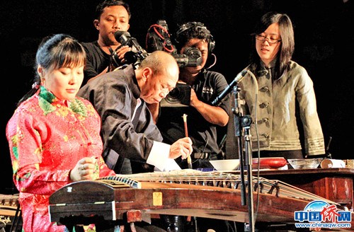 在中印尼宗教交流文藝演出中，作者（左二）和著古箏在寫中國(guó)書法。(圖片均由作者提供)