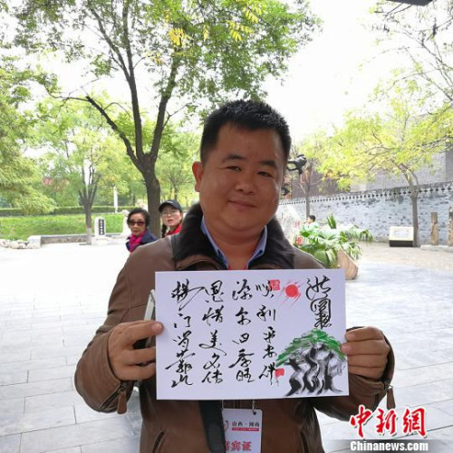 緬甸大其力大華學校負責人楊恩源在洪洞大槐樹景區(qū)向記者展示自己姓氏的文創(chuàng)產品。　楊杰英 攝