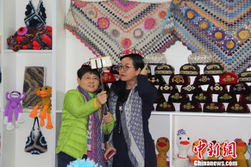 圖為海外華文媒體高層代表在第十二師頭屯河農(nóng)場同和幸福社區(qū)戴著女職工編織的小花帽拍照?！≡?攝
