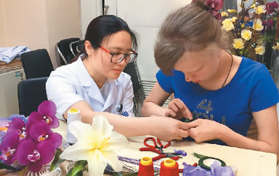醫(yī)護(hù)人員教俄羅斯患者瑪莎制作手工絲網(wǎng)花。 　　中國(guó)康復(fù)研究中心博愛醫(yī)院供圖