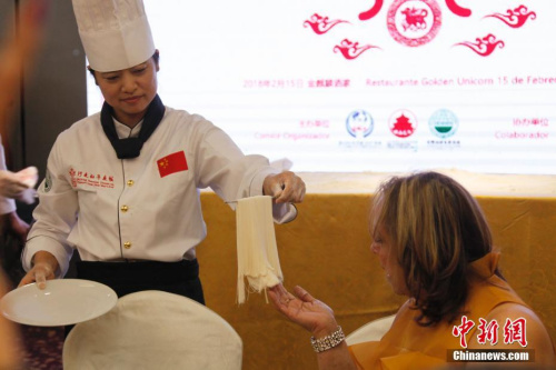 當(dāng)?shù)貢r(shí)間2月15日新春除夕夜，一餐“行走的年夜飯”拉開了巴拿馬華人社區(qū)慶祝中巴建交后首個(gè)農(nóng)歷新年一系列活動(dòng)的大幕。圖為廚藝大師請(qǐng)巴拿馬嘉賓近距離欣賞現(xiàn)場(chǎng)制作的細(xì)如發(fā)絲的龍須拉面。2018年“歡樂(lè)春節(jié)·行走的年夜飯”活動(dòng)由北京百年老字號(hào)“全聚德”和“東來(lái)順”組建廚藝大師團(tuán)隊(duì)，為巴拿馬當(dāng)?shù)赜押萌耸亢吐冒蛢S胞展現(xiàn)中華傳統(tǒng)烹飪技藝精萃，年夜飯菜點(diǎn)則精選中國(guó)各大菜系精華。<a target='_blank' >中新社</a>記者 余瑞冬 攝