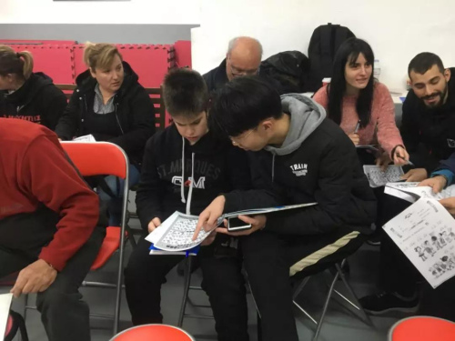 志愿者黃承輝(前排右一)輔導(dǎo)學(xué)員漢語(yǔ)拼音。(《歐洲時(shí)報(bào)》/蘇珊娜 攝)