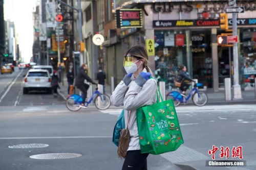 資料圖：當?shù)貢r間3月21日，美國紐約時代廣場一位行人防護嚴密。 圖片來源：中國新聞網(wǎng)