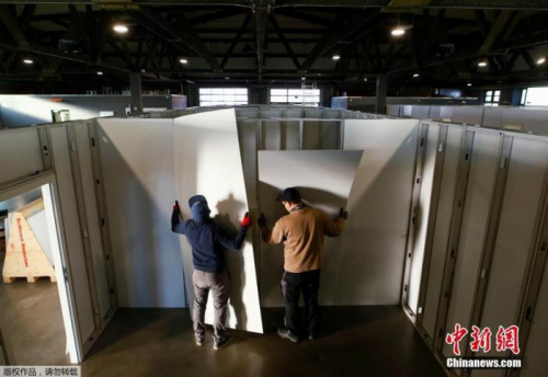 當(dāng)?shù)貢r(shí)間3月25日，德國希勒斯海姆，工作人員和志愿者將市政大廳改建為醫(yī)療中心用于收治新型冠狀病毒患者。圖為工作人員和志愿者在安裝醫(yī)療中心隔間的墻面。