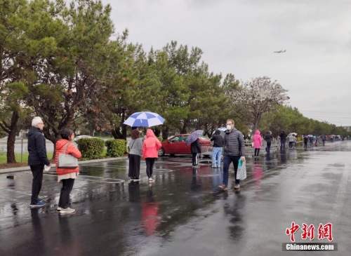 美國舊金山灣區(qū)民眾在位于福斯特城的Costco超市外冒雨排起長隊，等候購買物資。<a target='_blank' >中新社</a>記者 劉關(guān)關(guān) 攝