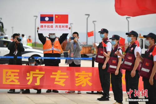 抗疫醫(yī)療專家組一行12人順利完成工作任務(wù)，乘包機(jī)平安飛抵云南昆明。圖為機(jī)場工作人員手舉印有中老兩國國旗的牌子迎接專家組。( <a target='_blank' >中新社</a>記者 劉冉陽 攝)