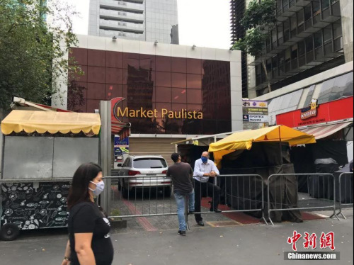 　當(dāng)?shù)貢r間5月1日，在巴西圣保羅，一位戴口罩的婦女從一家關(guān)閉的商場門前走過。<a target='_blank' >中新社</a>記者 莫成雄 攝