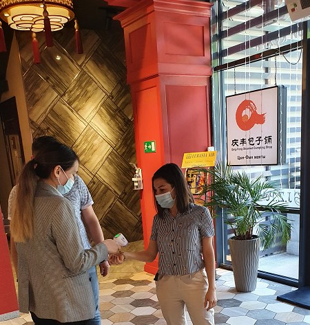 “九澤烤鴨”專設服務員給進店顧客測量體溫。(“哈薩克斯坦新觀察”微信公眾號)