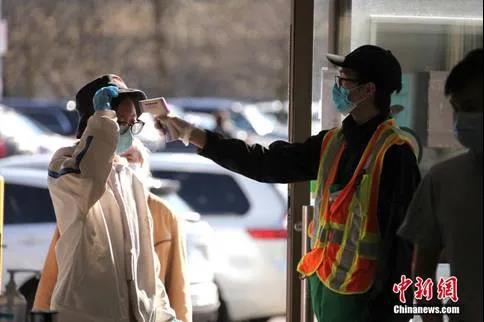 加拿大多倫多一家華人超市的工作人員在入口處對(duì)顧客逐一測(cè)量體溫。(<a target='_blank' >中新社</a>記者余瑞冬 攝)