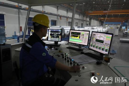 鼎力新材料公司的工廠投資1.2億美元，每年可以生產(chǎn)規(guī)格從5mic—2mm的鋁箔共計8萬噸。圖為技術(shù)員在操作切割鋁箔的軋機。人民網(wǎng)記者孫廣勇攝