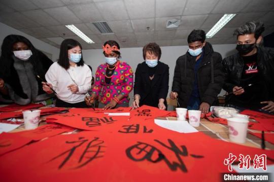 老師指導(dǎo)留學(xué)生在紅紙上寫對聯(lián)?！№f亮 攝