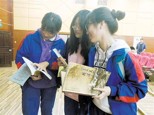 中國僑網(wǎng)同學(xué)們翻閱《五邑華僑義冢與跨洋遷葬》一書。