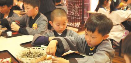 中國(guó)僑網(wǎng)聚隆光明中醫(yī)藥傳承教育中心的“小中醫(yī)”正在稱量中藥。